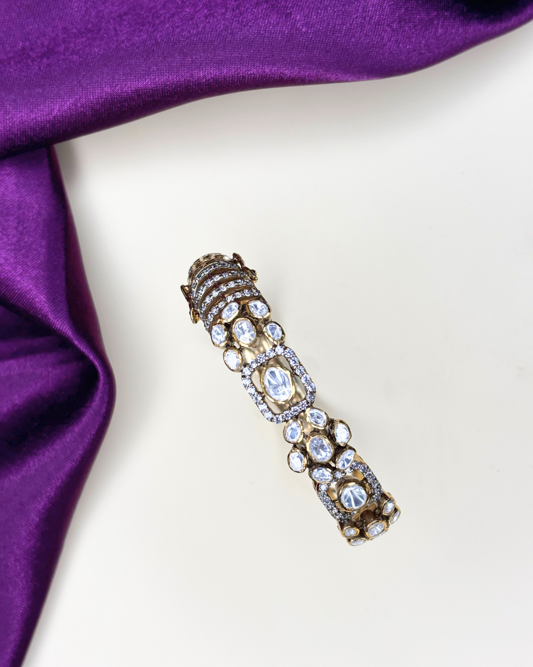 An ornate gold-toned bar cuff bracelet embellished with clear crystals and diamonds.