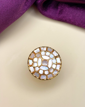A round gold-tone button embellished with a mosaic of white mother-of-pearl shell pieces.