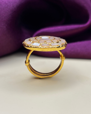 A gold ring with a large, round, scalloped shell inlay top.