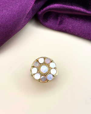 A gold-toned circular ring featuring a central white opal surrounded by smaller iridescent stones.