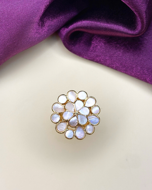 A gold flower-shaped brooch with iridescent white mother-of-pearl teardrop stones.