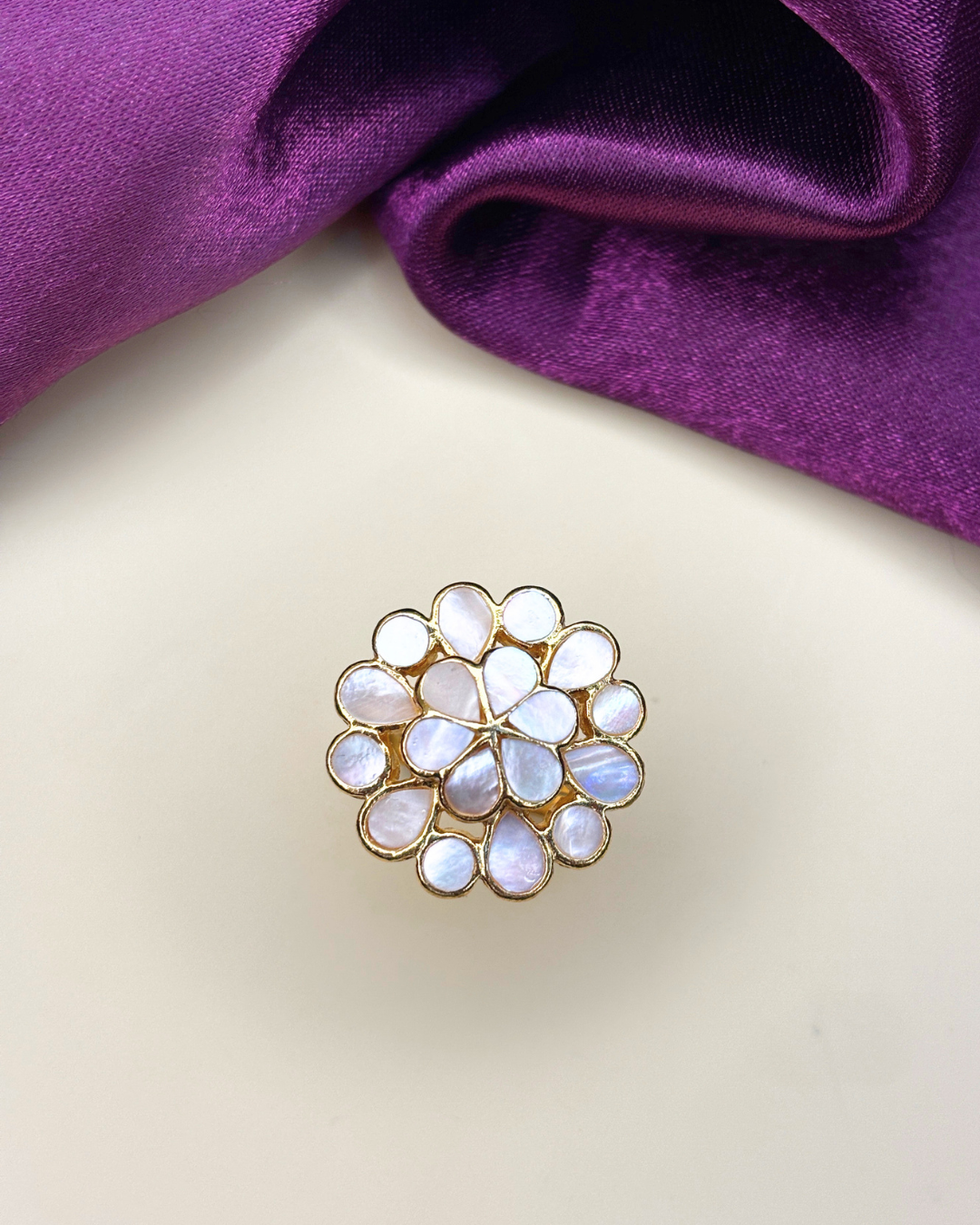 A gold flower-shaped brooch with iridescent white mother-of-pearl teardrop stones.