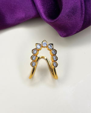 A gold U-shaped ring with seven clear round-cut gemstones.