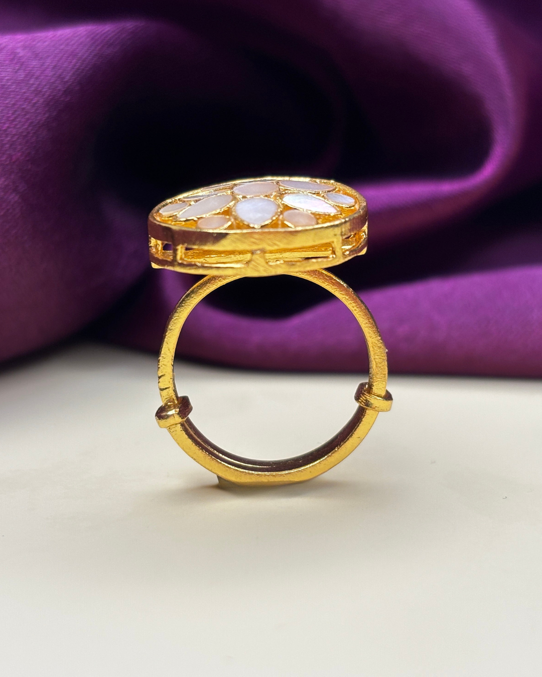 A gold ring with a large oval inlay of white stones.