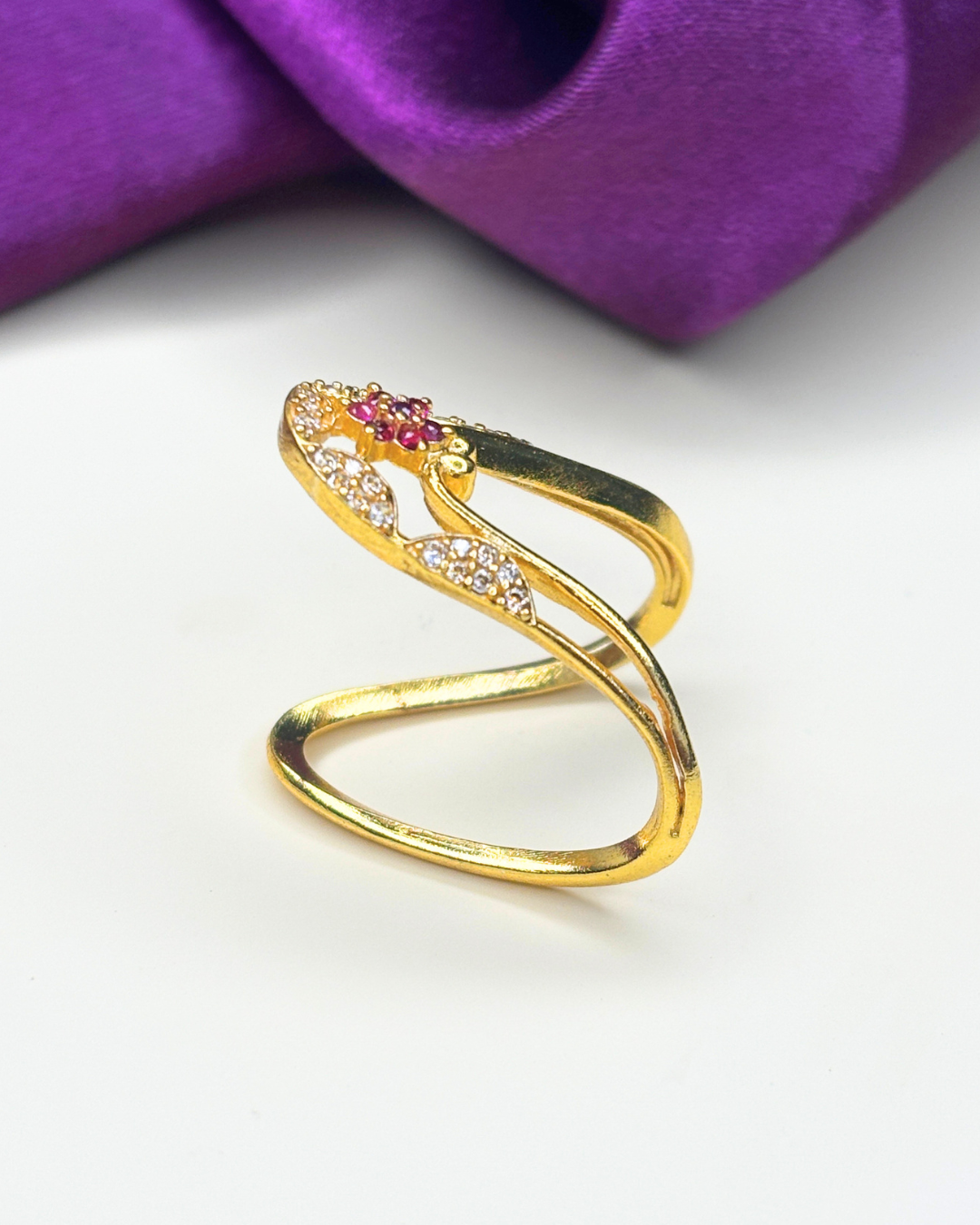 A gold-plated open ring with a curved top featuring a small pink gemstone