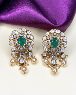 A pair of gold-plated statement earrings featuring oval-cut green emeralds.