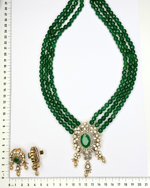 A traditional Indian multi-strand green bead necklace with a gold and green stone pendant.
