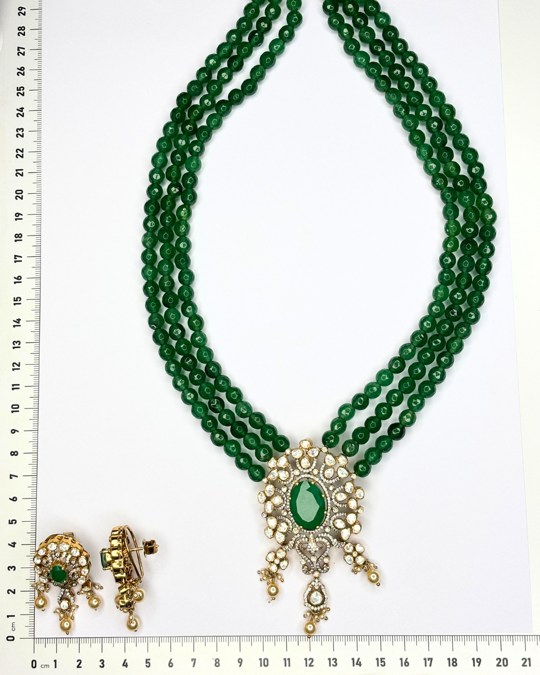 A traditional Indian multi-strand green bead necklace with a gold and green stone pendant.