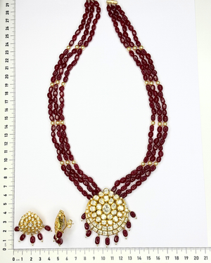 A traditional Indian jewelry set featuring a multi-strand maroon bead necklace.