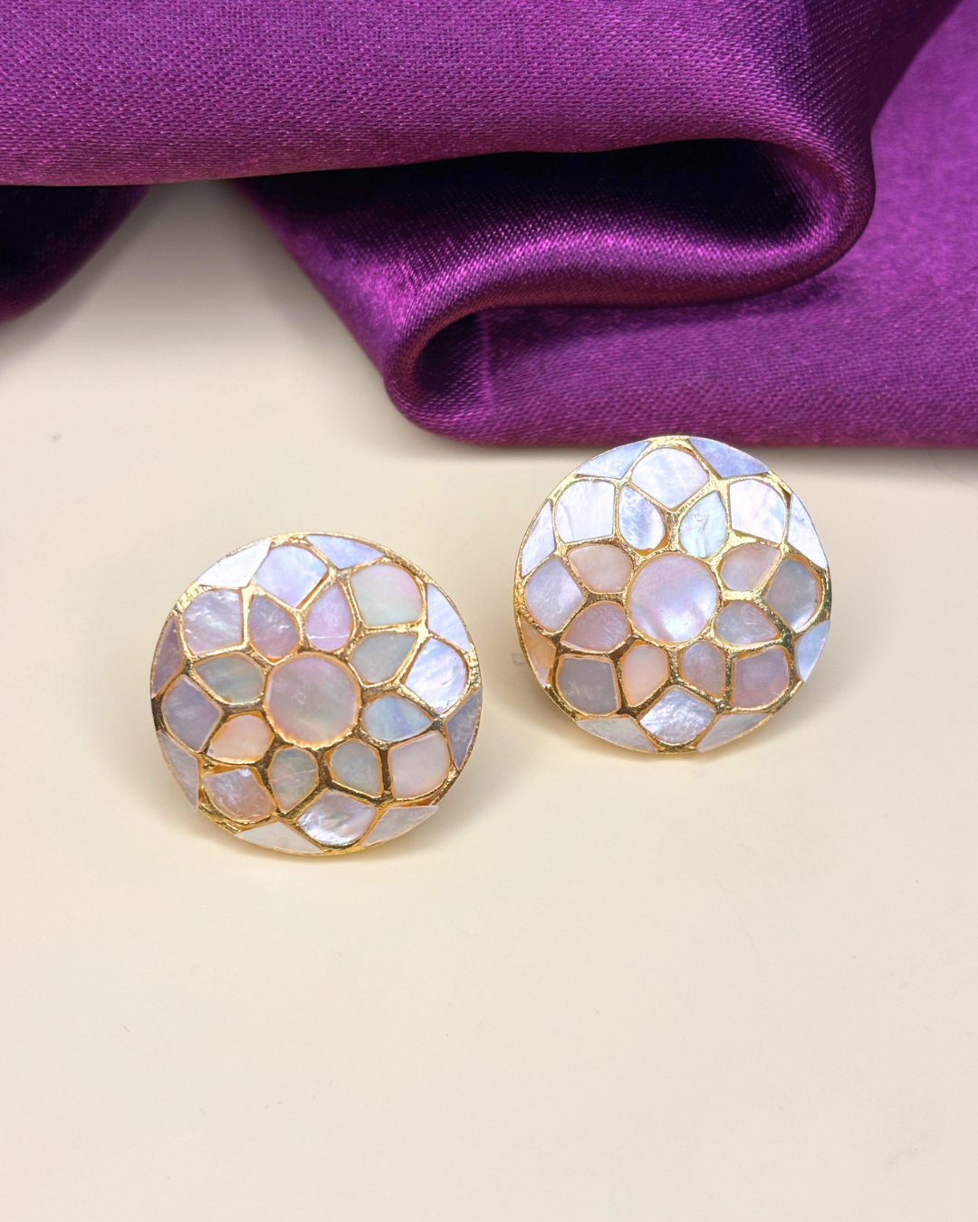 A pair of round stud earrings with an iridescent mother-of-pearl mosaic.