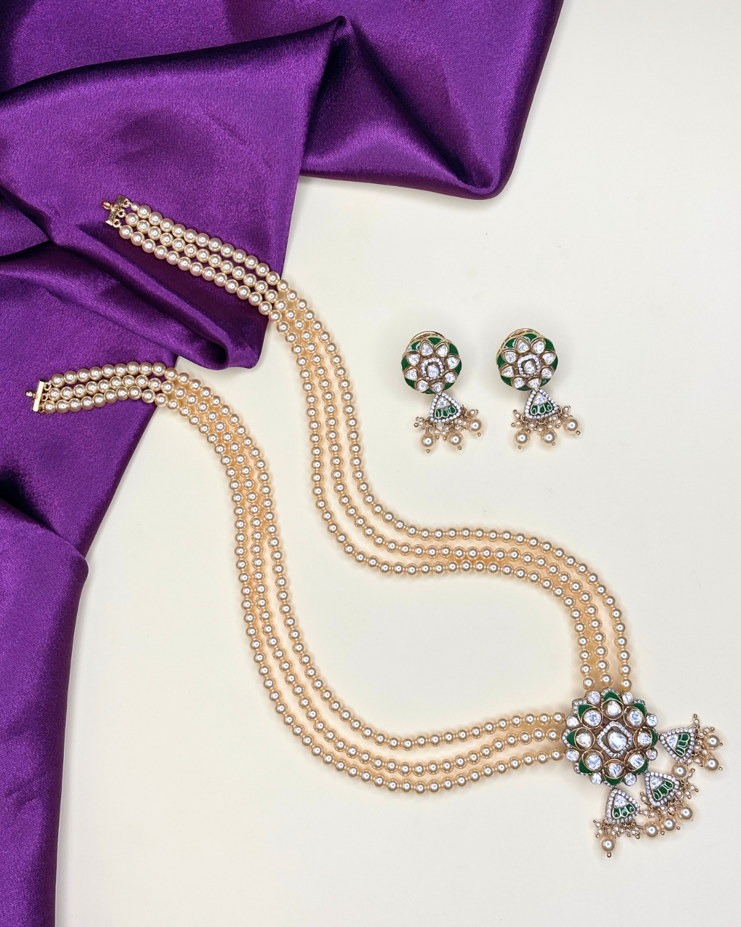 A traditional Indian jewelry set featuring a multi-strand pearl necklace and matching earrings.
