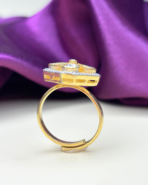 A gold ring with a decorative top featuring a small clear gemstone.