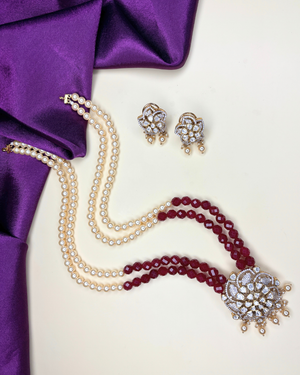 A traditional Indian jewelry set featuring a double-strand pearl necklace with a deep red beaded underlay.