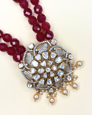 A close-up of a traditional Indian kundan necklace featuring a large gold-toned pendant adorned with clear kundan stones.