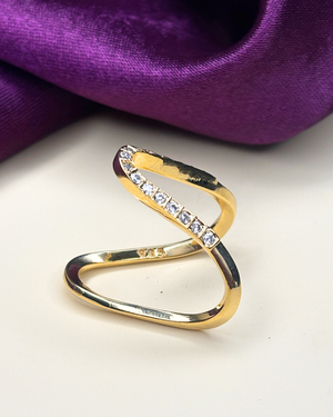 A gold-plated ring with a twisted, looped design and a row of clear square-cut stones.